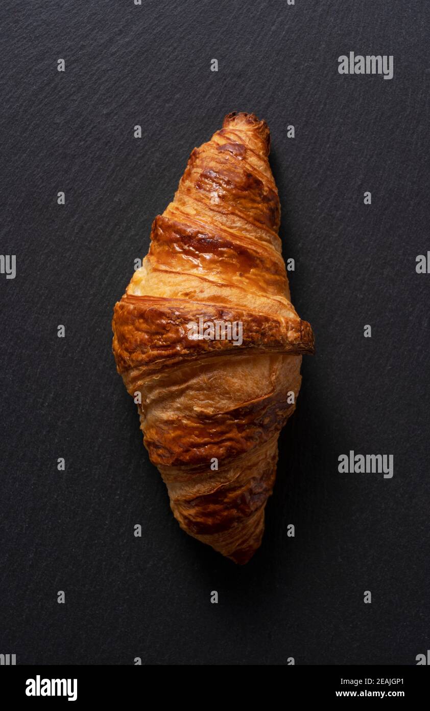 Croissant auf einem schwarzen Steinteller mit schwarzem Hintergrund Stockfoto