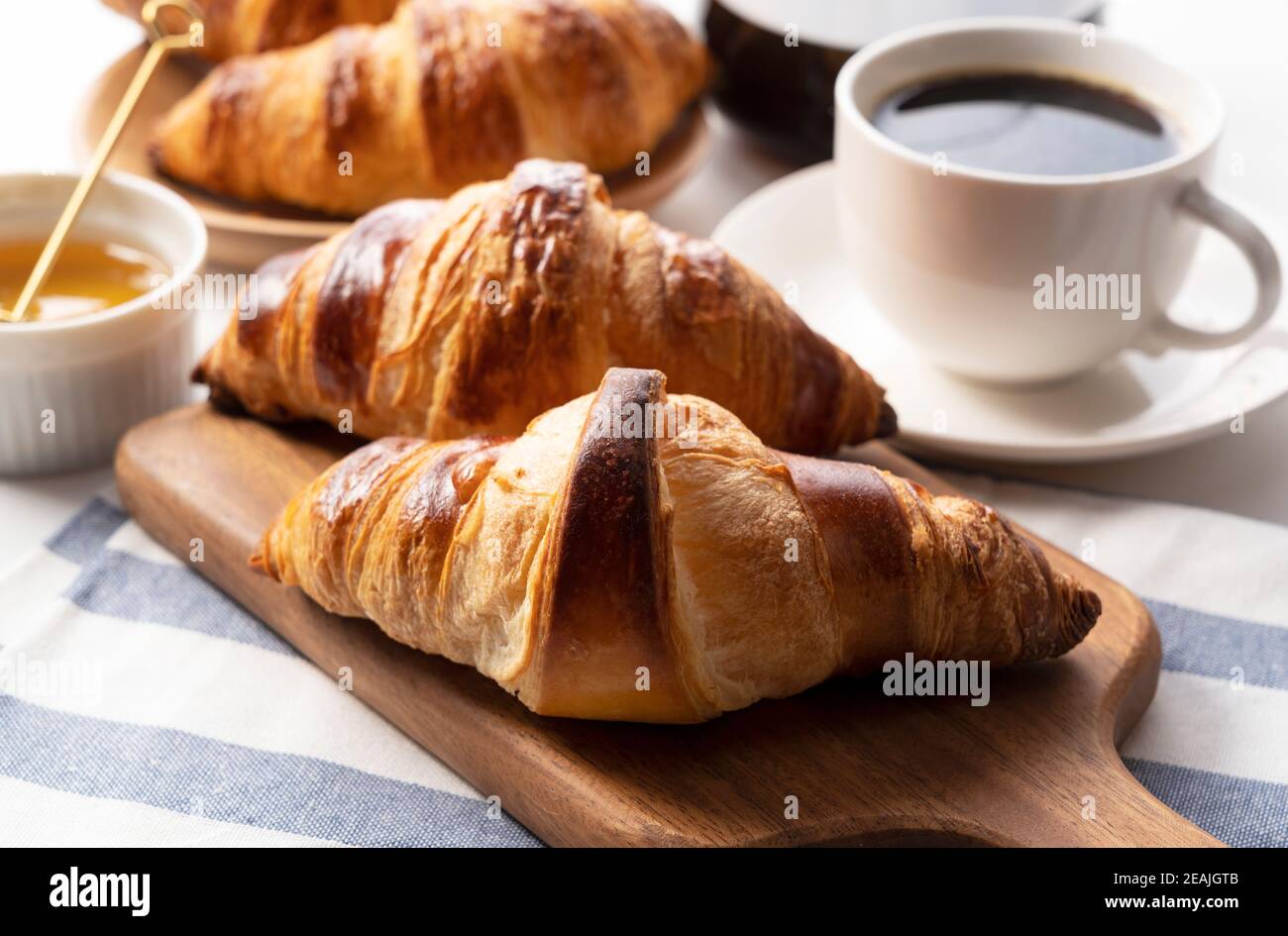 Ein Croissant und Kaffee und Honig dahinter Stockfoto