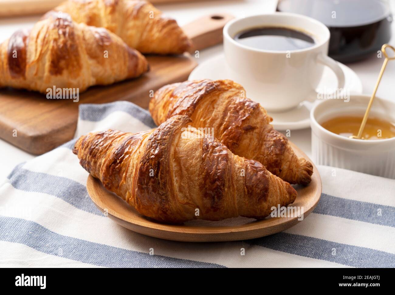 Ein Croissant und Kaffee und Honig dahinter Stockfoto