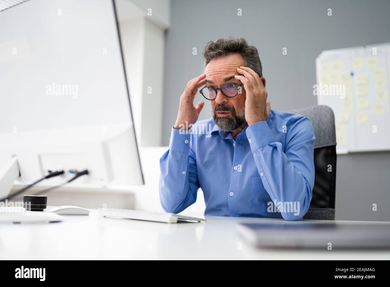 Sorge Geschäftsmann Mit Migräne Bei Computer Stockfoto