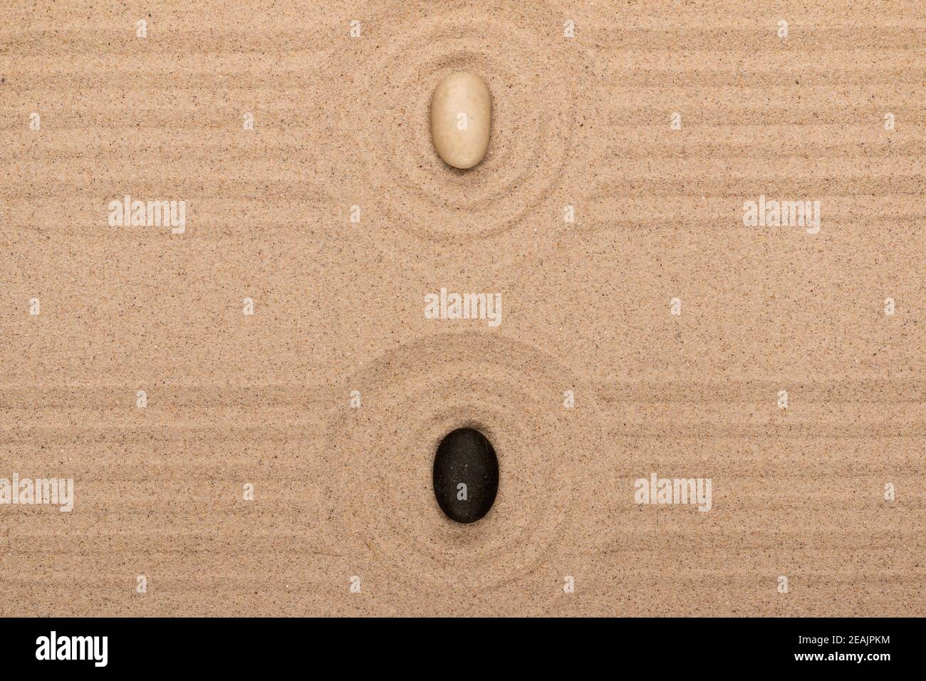 Zwei Steine liegen in der Mitte eines Sandkreises. Sommerkonzept. Stockfoto