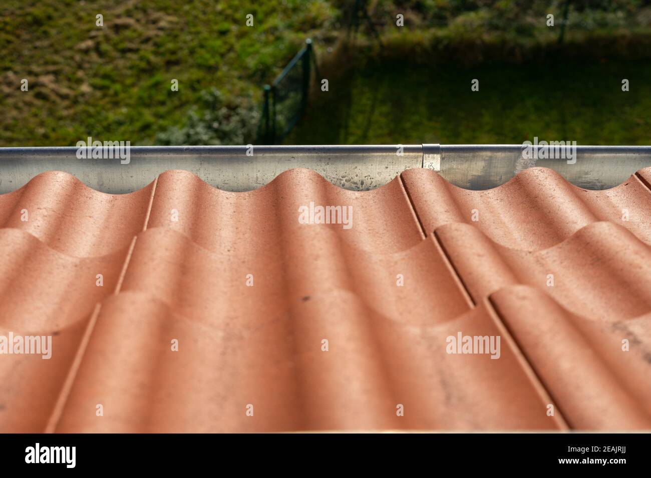 Rote Dachziegel auf dem Dach mit Regenrinne in Sonnenschein Stockfoto