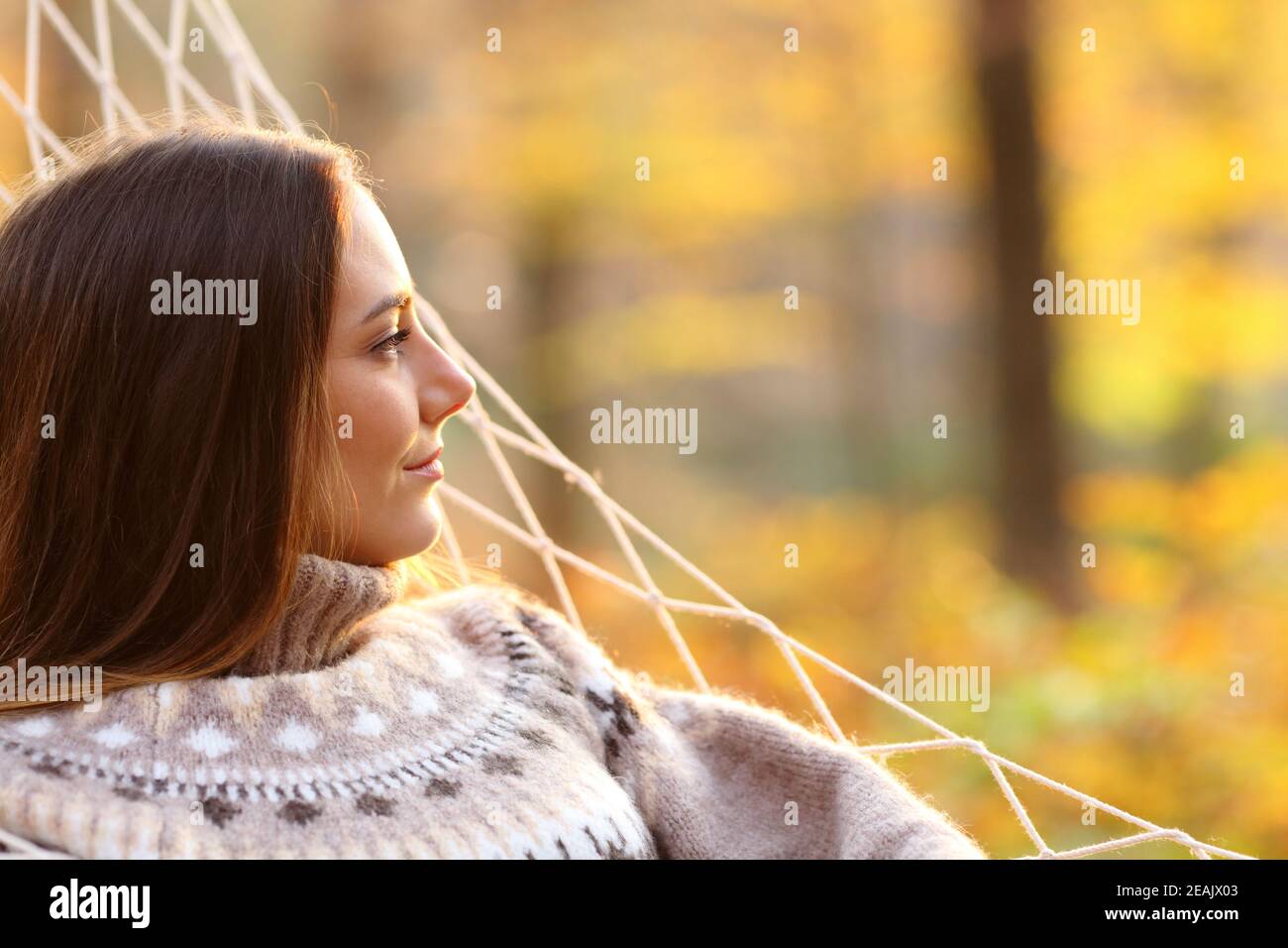 Entspannte Frau, die im Herbst in der Hängematte nachdenkt Stockfoto