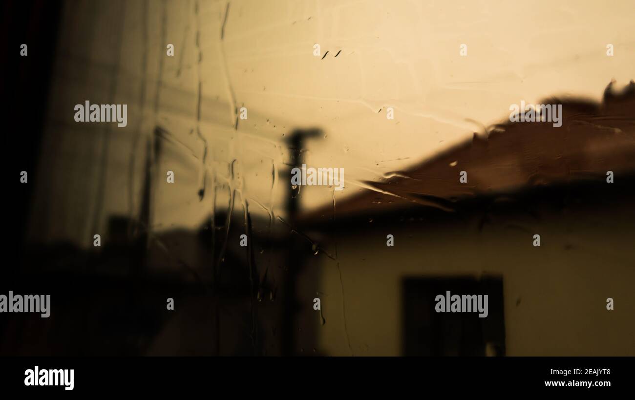Wasser auf dem Fenster. Regen auf das Fensterglas. Schatten auf Baum und Natur durch Glas und Regen. Schatten des Gebäudes Stockfoto