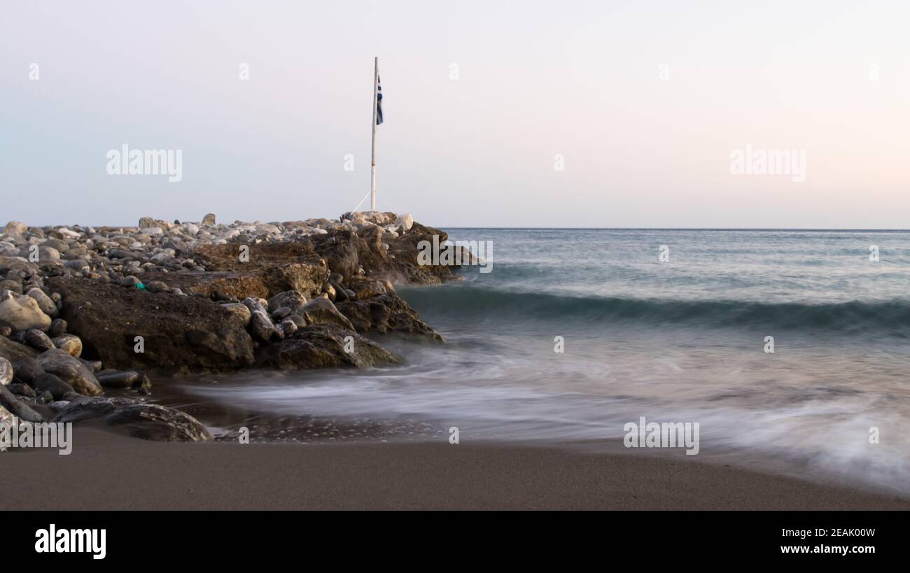 Seeufer in Keratokampos, Kreta mit einem Steg aus Steinen und klarem Himmel Stockfoto