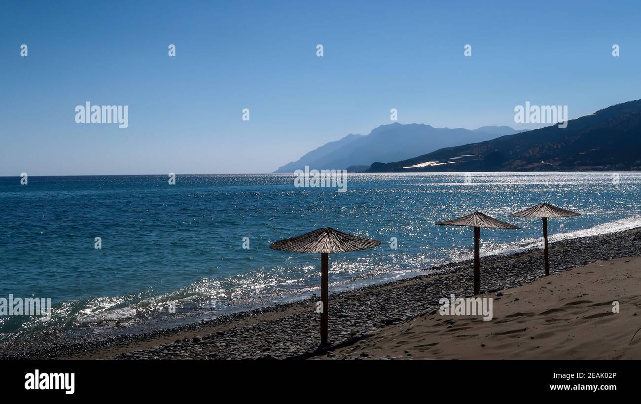 Heuschirme am Strand und Berge weit weg - Keratokampos, Kreta Stockfoto