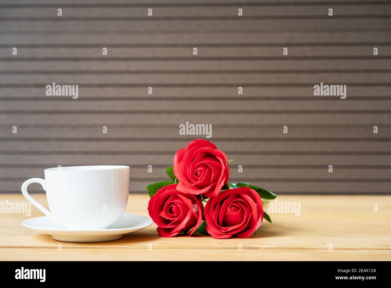 Rote Rose und Kaffeetasse auf Holz Stockfoto