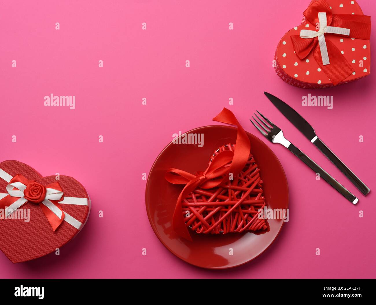 Geschenkbox und runde Keramikplatte und Gabel mit Messer Auf einem rosa Hintergrund Stockfoto