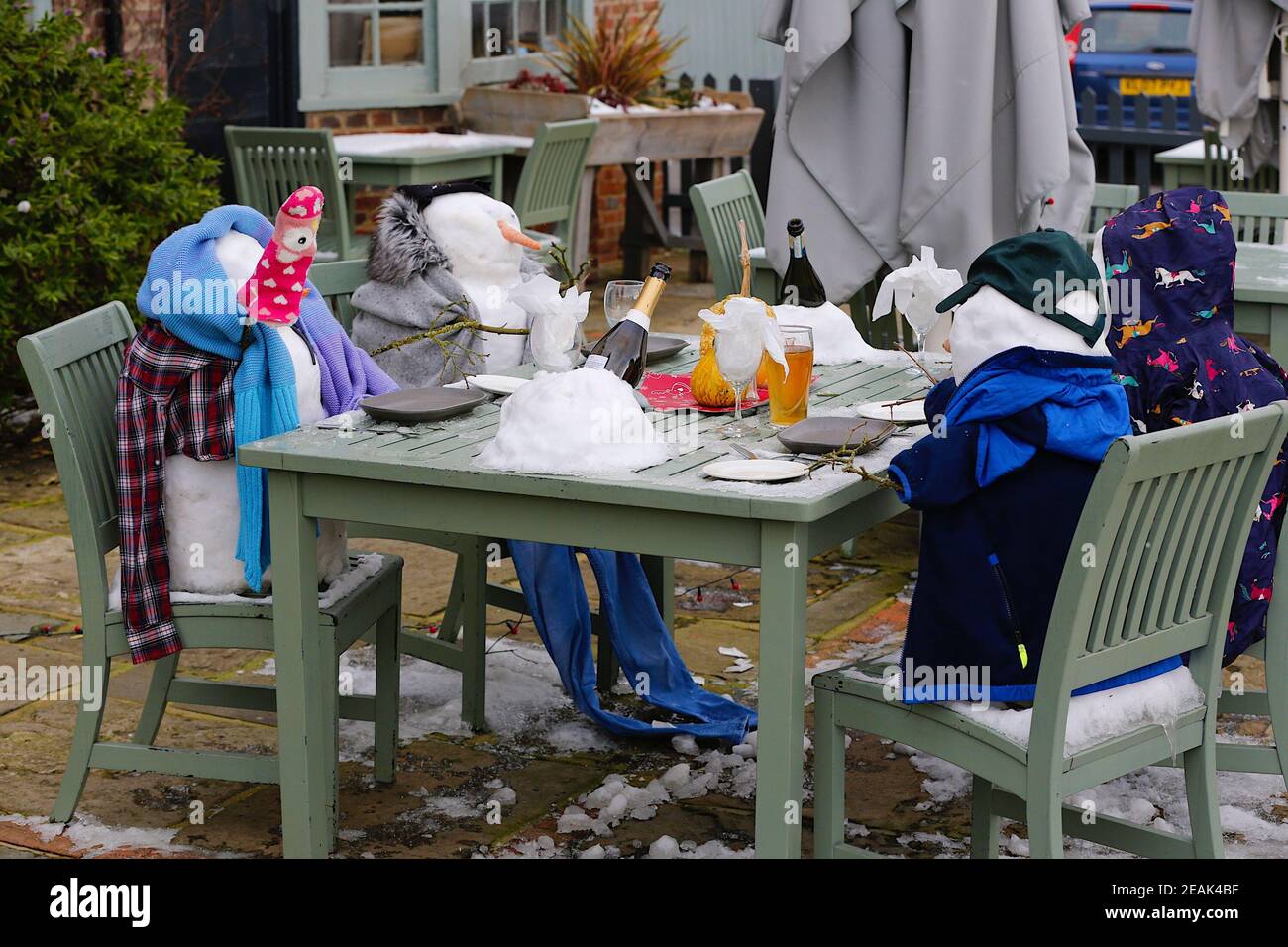Ashford, Kent, Großbritannien. 10. Februar 2021. Aufgrund der Pandemie musste das Chequers on the Green Pub an der Ashford Rd A28 in High Halden schließen und hat eine neuartige Möglichkeit entwickelt, Passanten mit Schnee zu amüsieren, der von Storm Darcy kommt. Eine Familie von Schneefiguren sitzt draußen, trinkt und isst. Foto-Kredit: Paul Lawrenson/Alamy Live Nachrichten Stockfoto