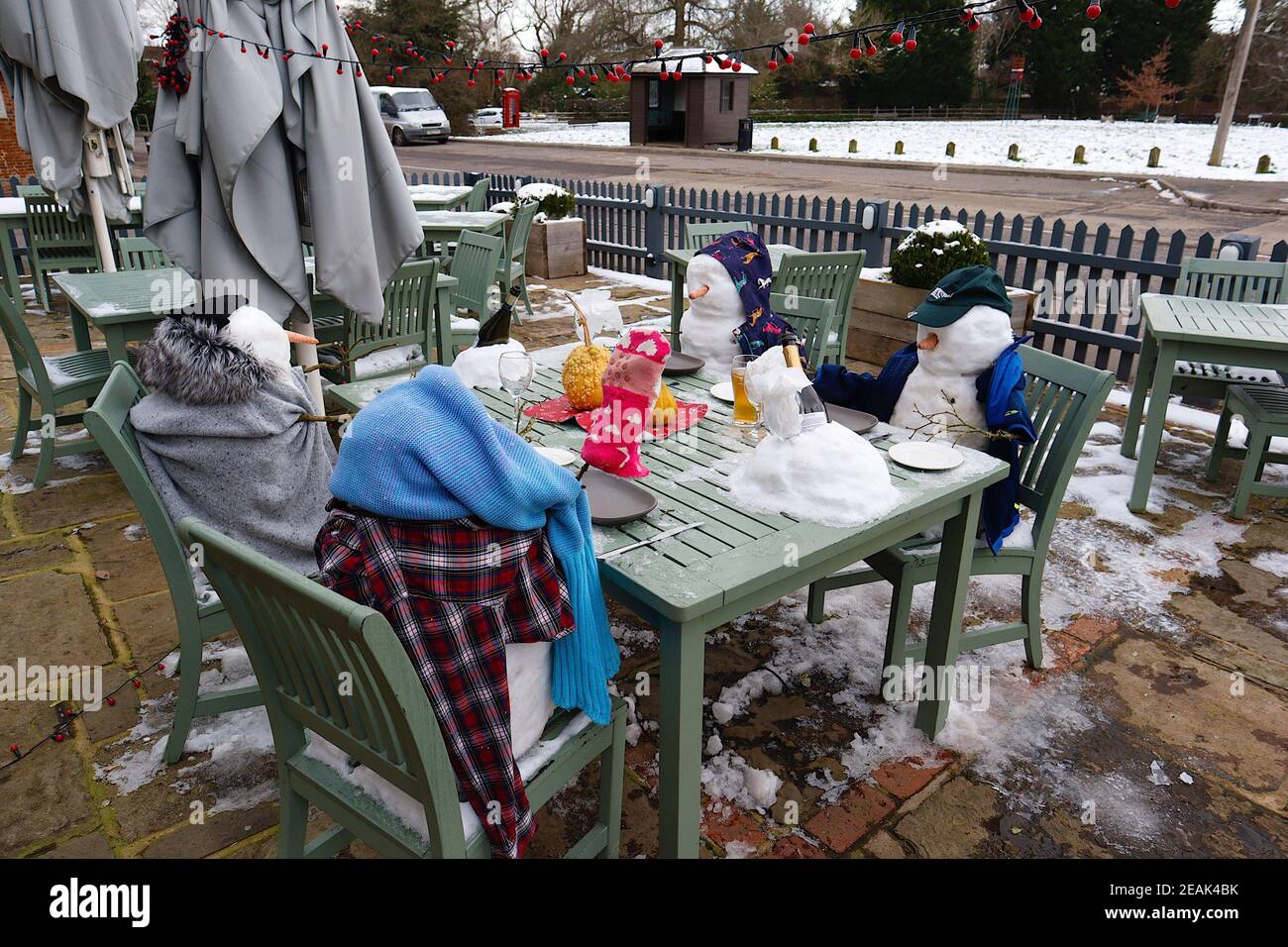 Ashford, Kent, Großbritannien. 10. Februar 2021. Aufgrund der Pandemie musste das Chequers on the Green Pub an der Ashford Rd A28 in High Halden schließen und hat eine neuartige Möglichkeit entwickelt, Passanten mit Schnee zu amüsieren, der von Storm Darcy kommt. Eine Familie von Schneefiguren sitzt draußen, trinkt und isst. Foto-Kredit: Paul Lawrenson/Alamy Live Nachrichten Stockfoto