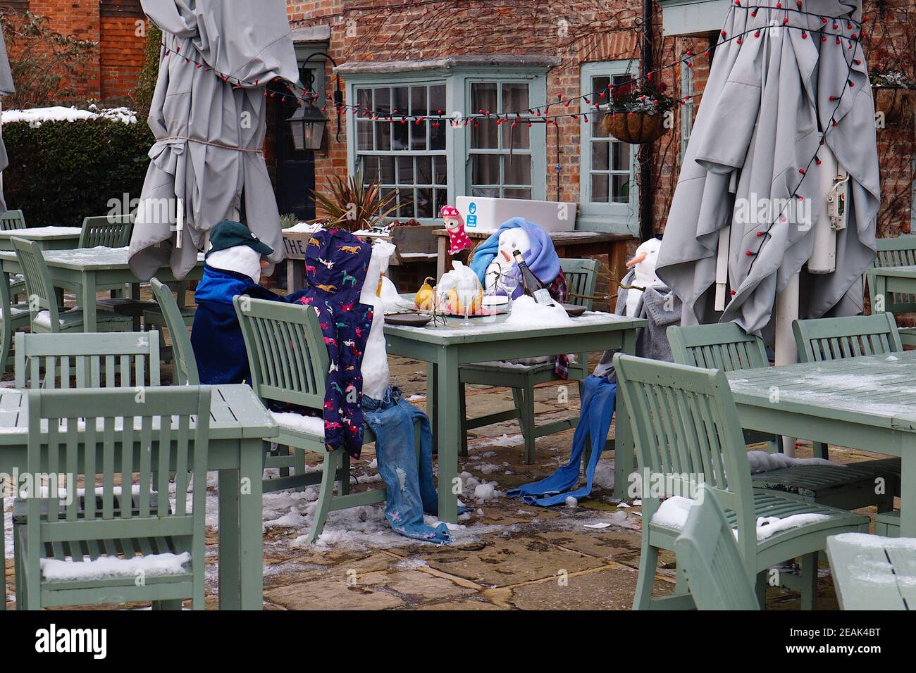 Ashford, Kent, Großbritannien. 10. Februar 2021. Aufgrund der Pandemie musste das Chequers on the Green Pub an der Ashford Rd A28 in High Halden schließen und hat eine neuartige Möglichkeit entwickelt, Passanten mit Schnee zu amüsieren, der von Storm Darcy kommt. Eine Familie von Schneefiguren sitzt draußen, trinkt und isst. Foto-Kredit: Paul Lawrenson/Alamy Live Nachrichten Stockfoto