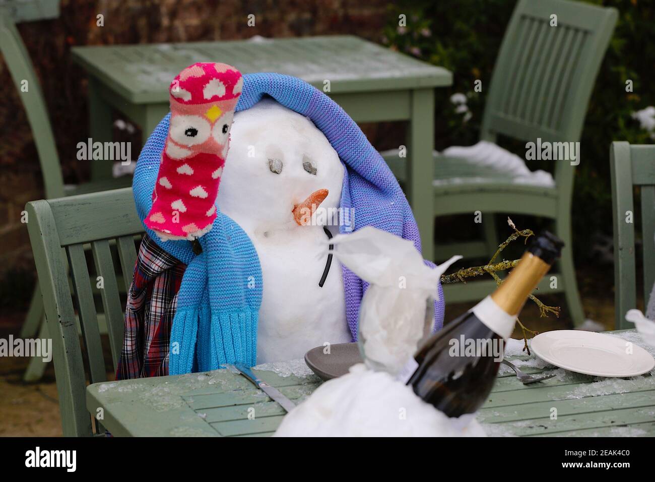 Ashford, Kent, Großbritannien. 10. Februar 2021. Aufgrund der Pandemie musste das Chequers on the Green Pub an der Ashford Rd A28 in High Halden schließen und hat eine neuartige Möglichkeit entwickelt, Passanten mit Schnee zu amüsieren, der von Storm Darcy kommt. Eine Familie von Schneefiguren sitzt draußen, trinkt und isst. Foto-Kredit: Paul Lawrenson/Alamy Live Nachrichten Stockfoto