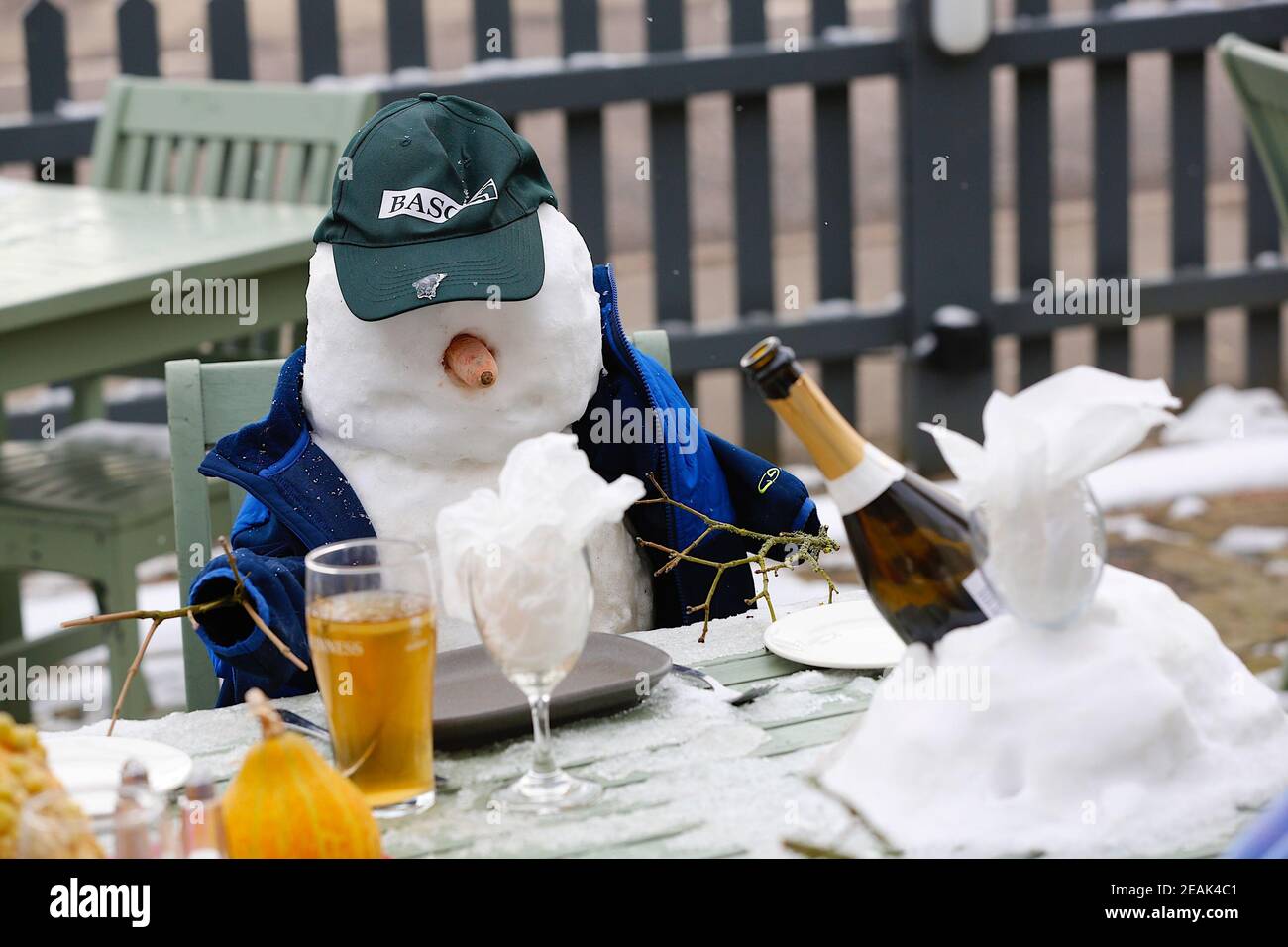 Ashford, Kent, Großbritannien. 10. Februar 2021. Aufgrund der Pandemie musste das Chequers on the Green Pub an der Ashford Rd A28 in High Halden schließen und hat eine neuartige Möglichkeit entwickelt, Passanten mit Schnee zu amüsieren, der von Storm Darcy kommt. Eine Familie von Schneefiguren sitzt draußen, trinkt und isst. Foto-Kredit: Paul Lawrenson/Alamy Live Nachrichten Stockfoto