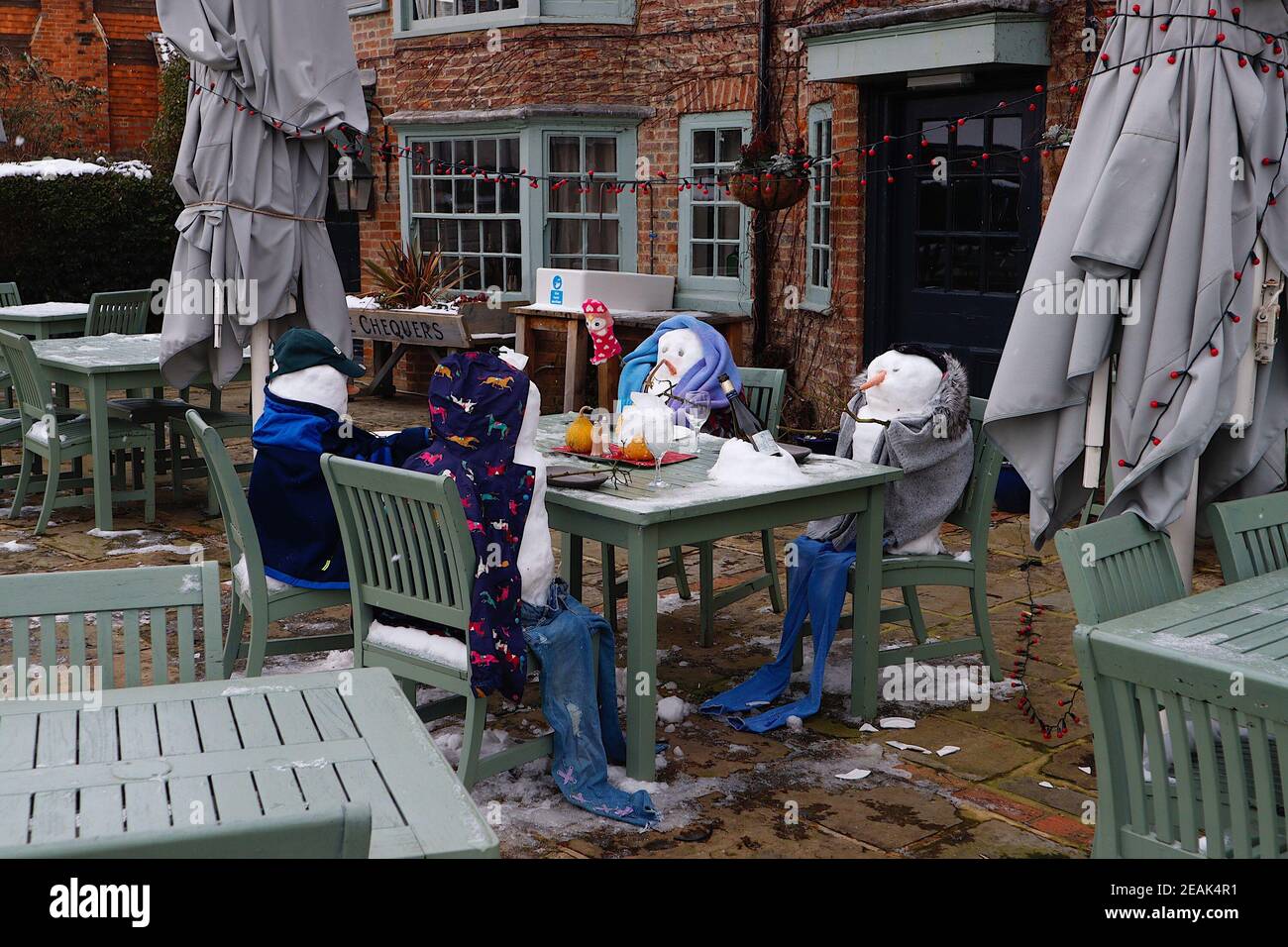 Ashford, Kent, Großbritannien. 10. Februar 2021. Aufgrund der Pandemie musste das Chequers on the Green Pub an der Ashford Rd A28 in High Halden schließen und hat eine neuartige Möglichkeit entwickelt, Passanten mit Schnee zu amüsieren, der von Storm Darcy kommt. Eine Familie von Schneefiguren sitzt draußen, trinkt und isst. Foto-Kredit: Paul Lawrenson/Alamy Live Nachrichten Stockfoto