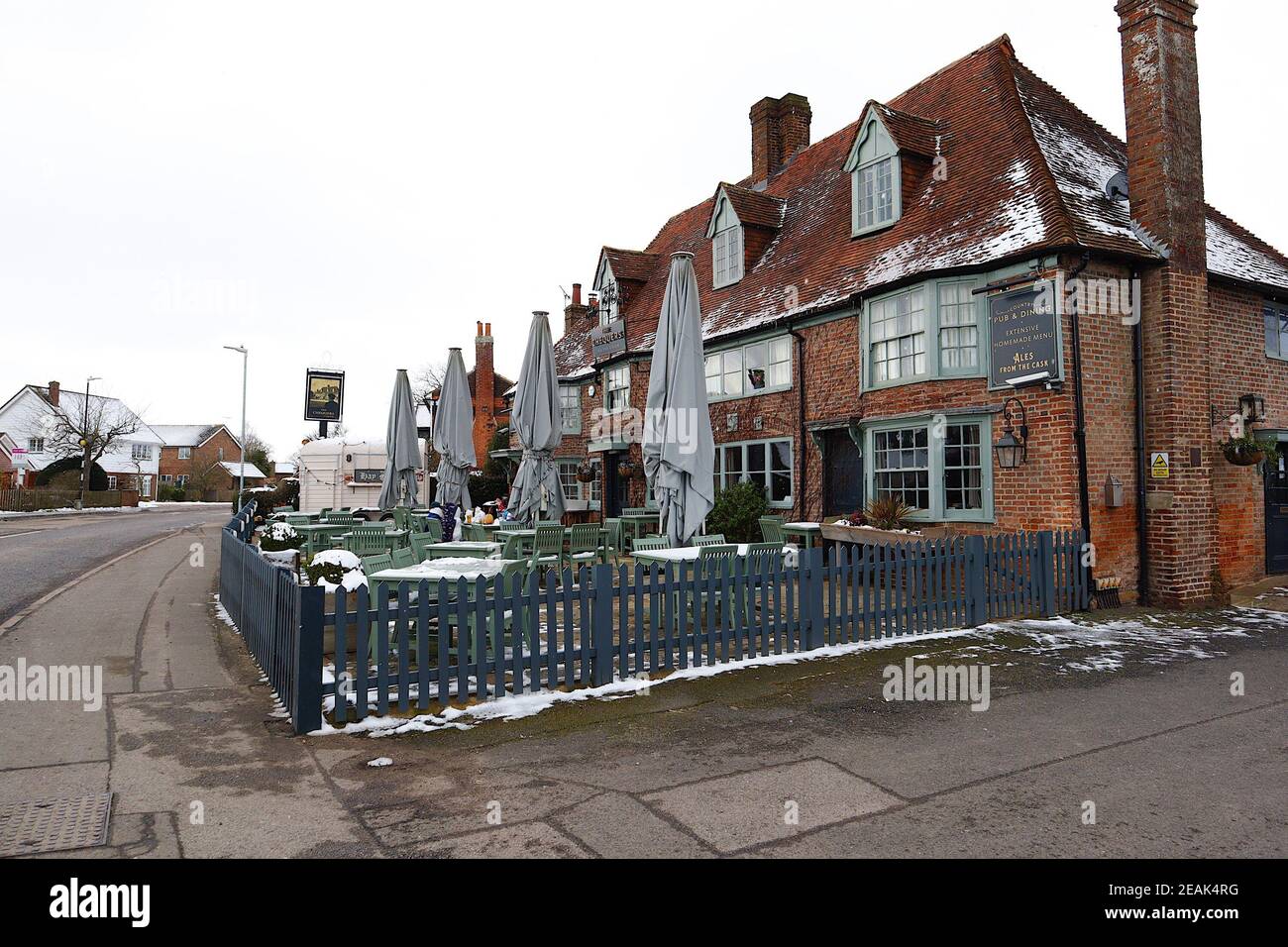 Ashford, Kent, Großbritannien. 10. Februar 2021. Aufgrund der Pandemie musste das Chequers on the Green Pub an der Ashford Rd A28 in High Halden schließen und hat eine neuartige Möglichkeit entwickelt, Passanten mit Schnee zu amüsieren, der von Storm Darcy kommt. Eine Familie von Schneefiguren sitzt draußen, trinkt und isst. Foto-Kredit: Paul Lawrenson/Alamy Live Nachrichten Stockfoto