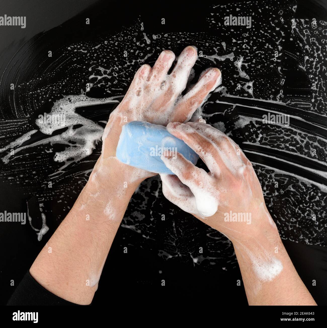 Prozess der Händewaschen mit blauer Seife, Teile des Körpers in weißem Schaum auf schwarzem Hintergrund Stockfoto