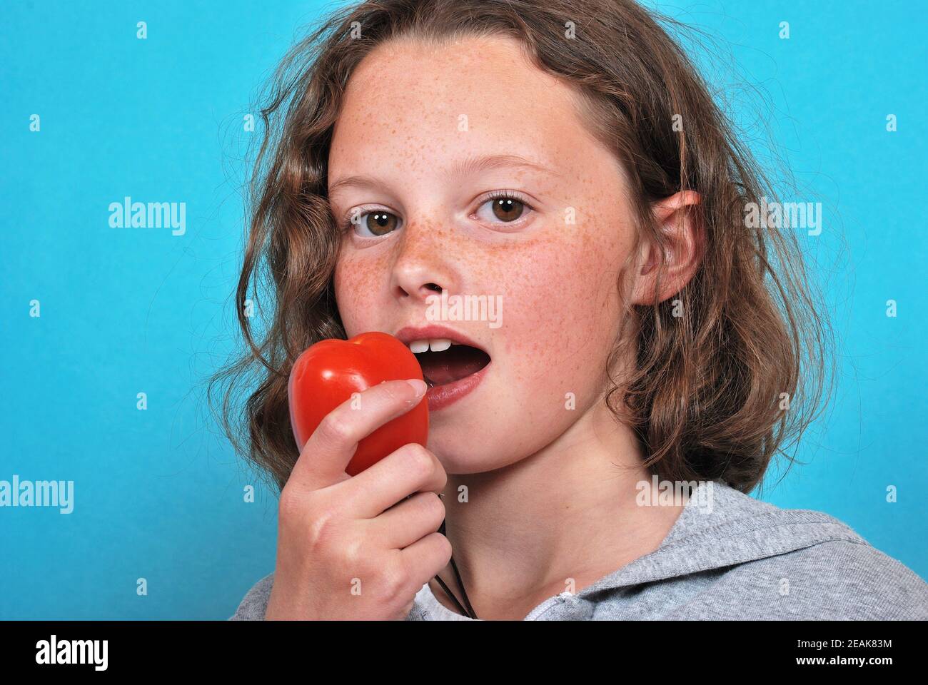Mädchen essen eine Tomate Stockfoto