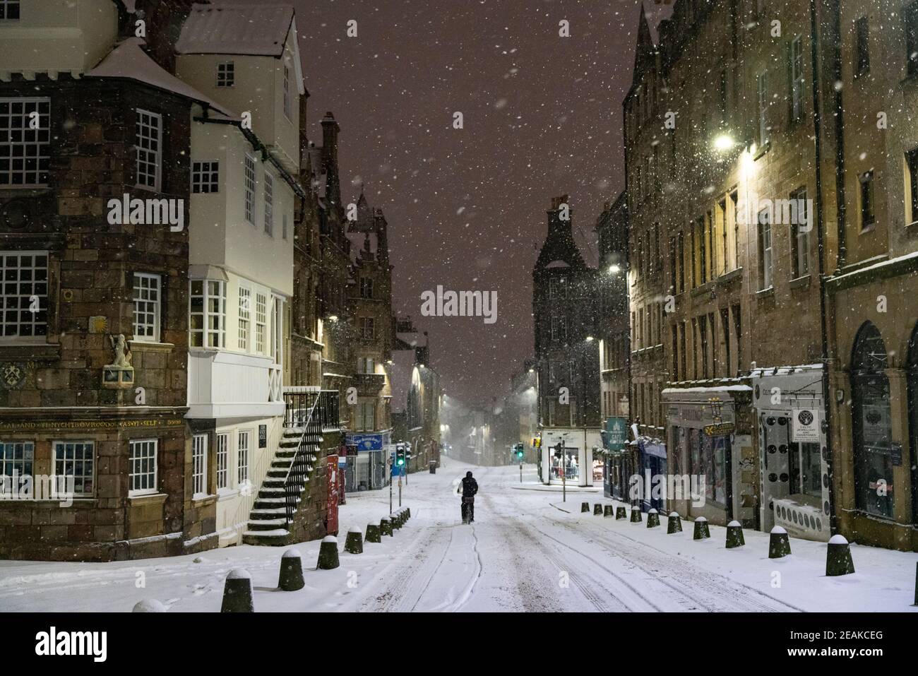 Edinburgh, Schottland, Großbritannien. Februar 2021, 10. Große Frost in Großbritannien mit schweren Nacht-und Morgenschnee in der Stadt weiter. Pic; EIN Radfahrer fährt vorsichtig die Royal Mile am John Knox House hinunter. Iain Masterton/Alamy Live Nachrichten Stockfoto