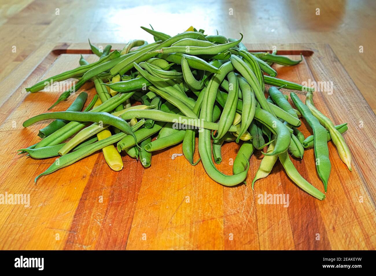 Frische grüne Bohnen in der Mitte eines Schneidebretts Stockfoto