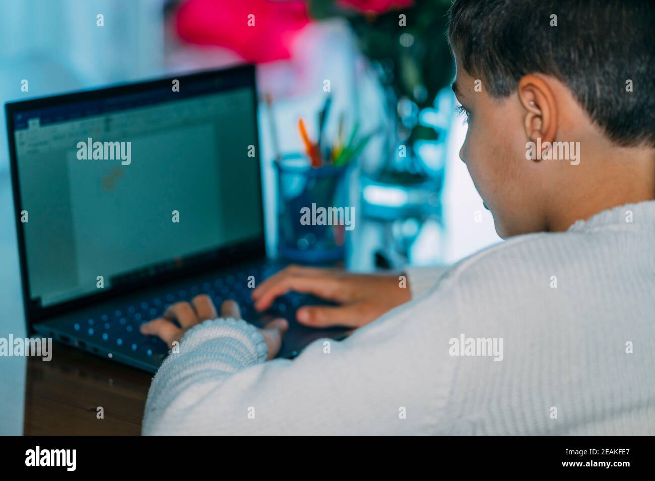 Das Kind nutzt Laptop-Computer zu Hause. Beißt einen Stift. Horizontales Foto. Stockfoto