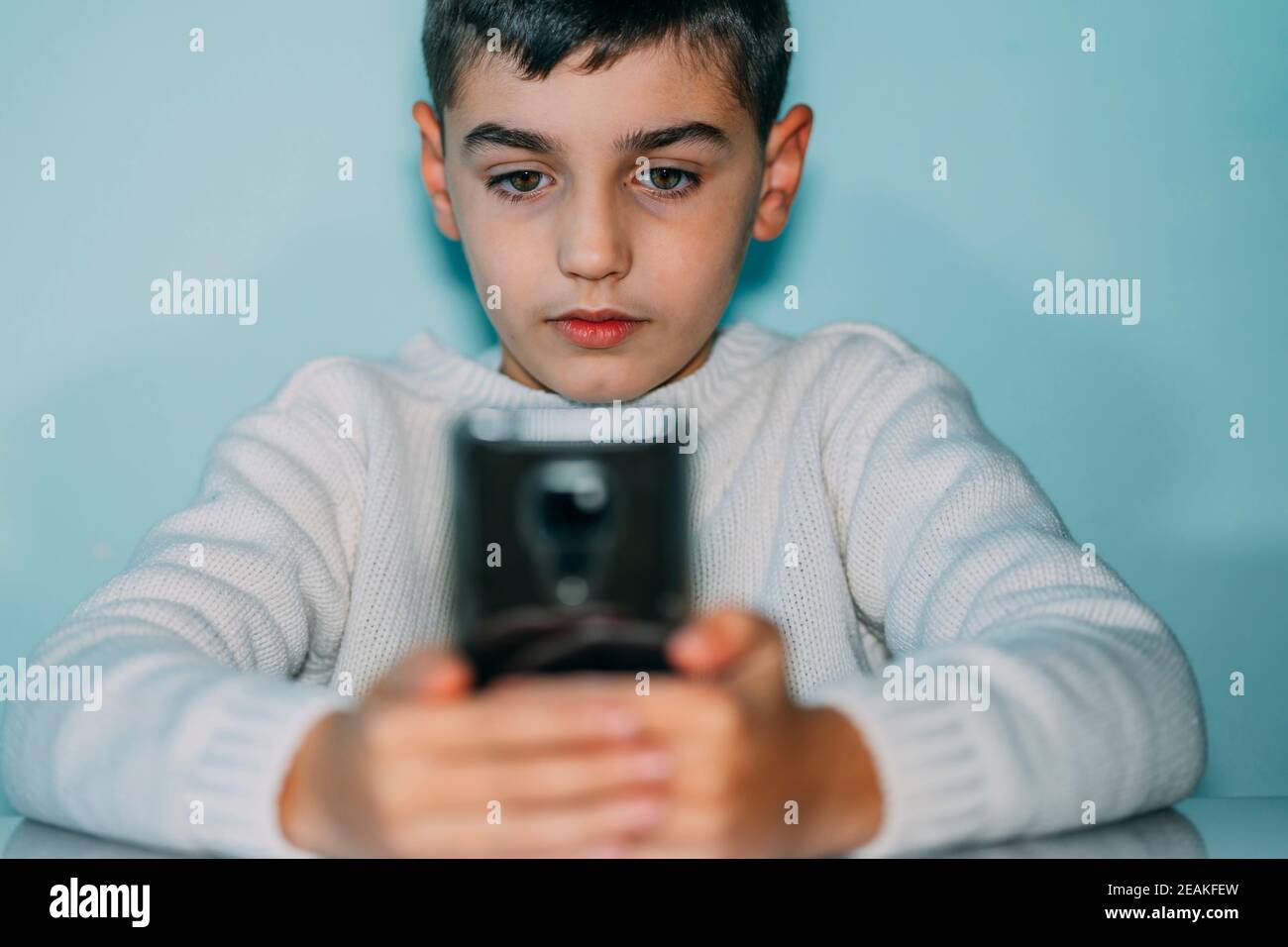 Kind mit Smartphone , suchen ernst. Horizontales Foto Stockfoto