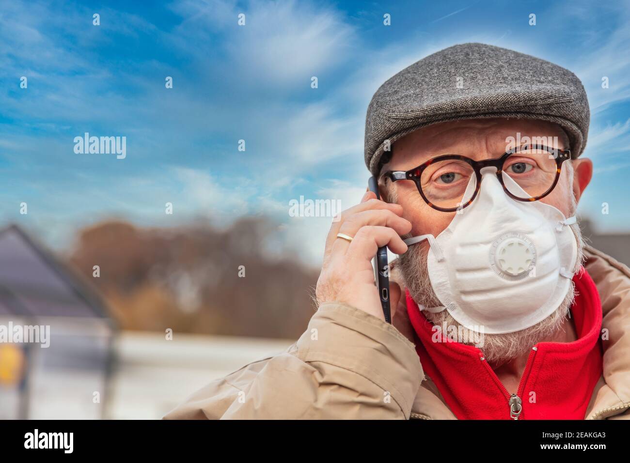 Senior mit Gesichtsmaske über Handy Stockfoto