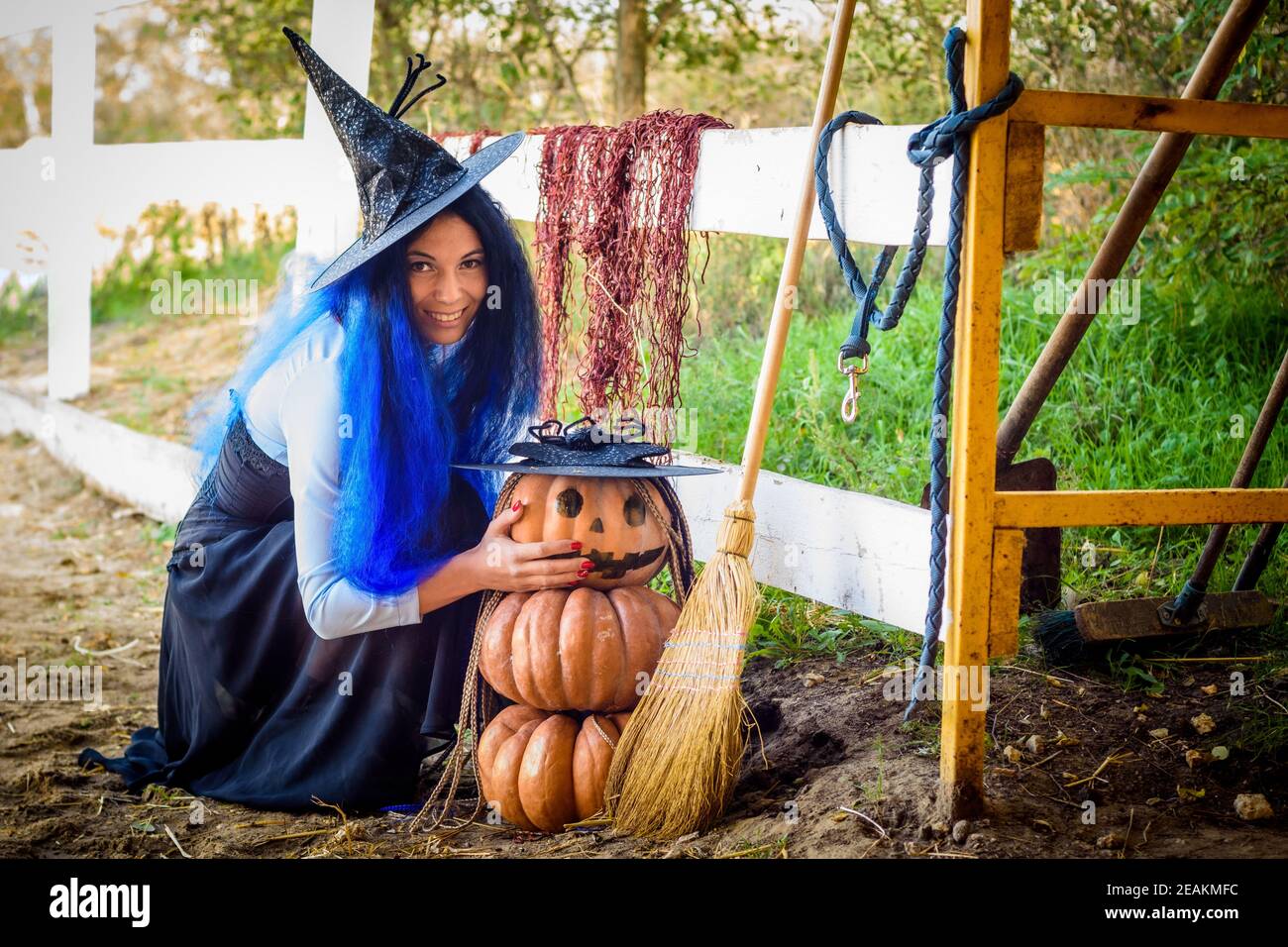 Ein Mädchen in einem Hexenkostüm, feiert Halloween, setzte sich von einem Kürbis mit einem gezeichneten bösartigen Grimasse Stockfoto