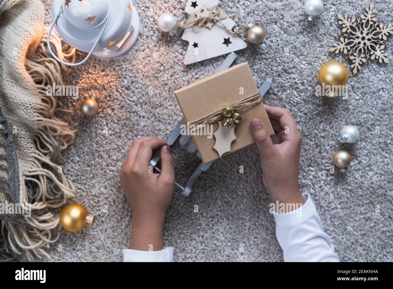 Weihnachtshintergrund mit gemütlicher Winteratmosphäre. Kinderhände mit dem Geschenk für das neue Jahr. Stockfoto