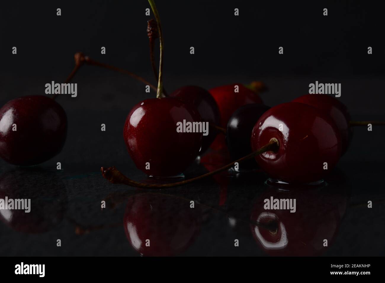 Kirschen, mit Wassertropfen auf schwarzem Hintergrund mit Spiegelung Stockfoto