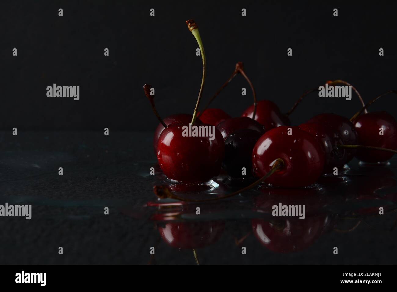 Kirschen, mit Wassertropfen auf schwarzem Hintergrund mit Spiegelung Stockfoto