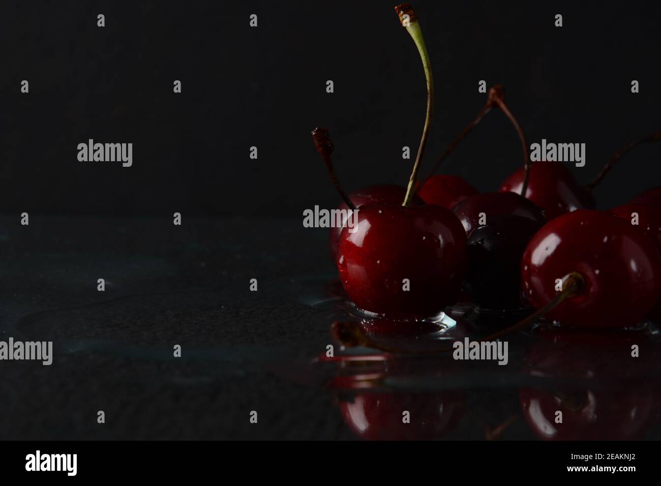 Kirschen, mit Wassertropfen auf schwarzem Hintergrund mit Spiegelung Stockfoto