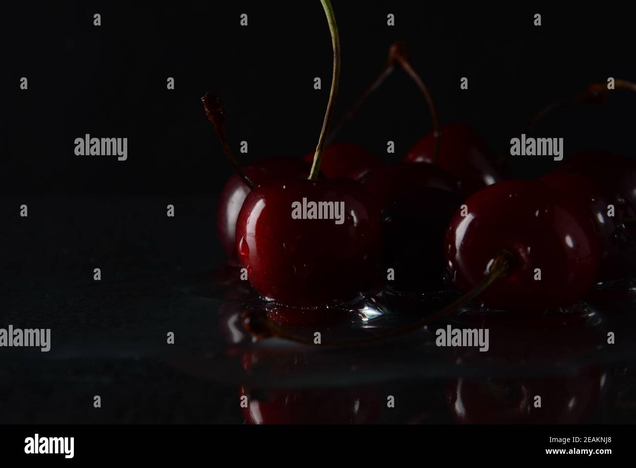 Kirschen, mit Wassertropfen auf schwarzem Hintergrund mit Spiegelung Stockfoto