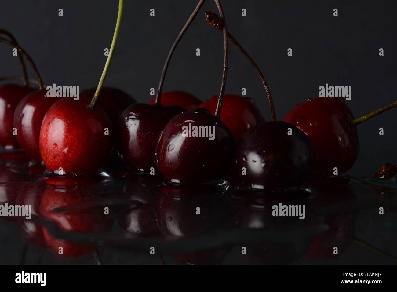 Kirschen, mit Wassertropfen auf schwarzem Hintergrund mit Spiegelung Stockfoto