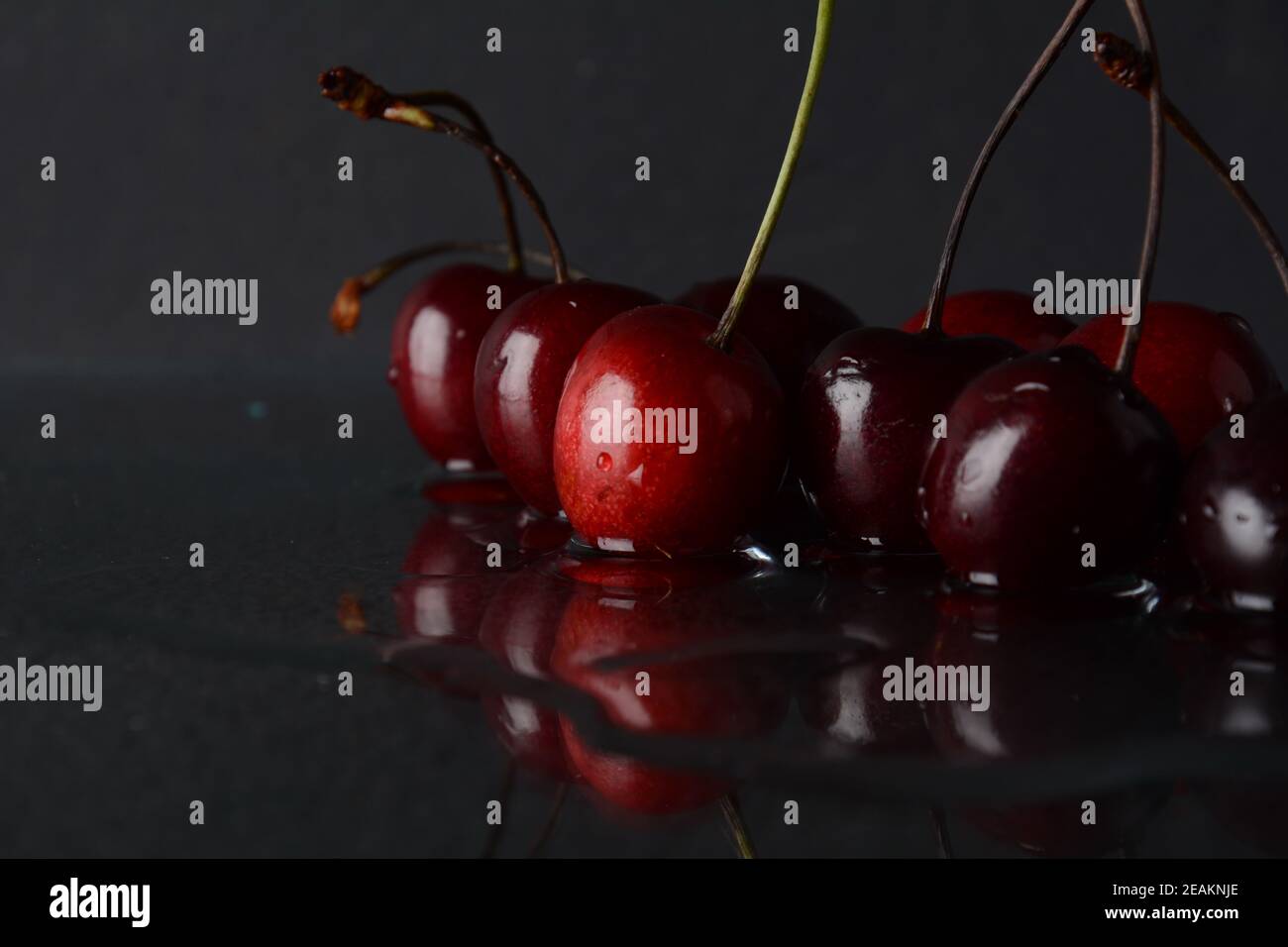 Kirschen, mit Wassertropfen auf schwarzem Hintergrund mit Spiegelung Stockfoto