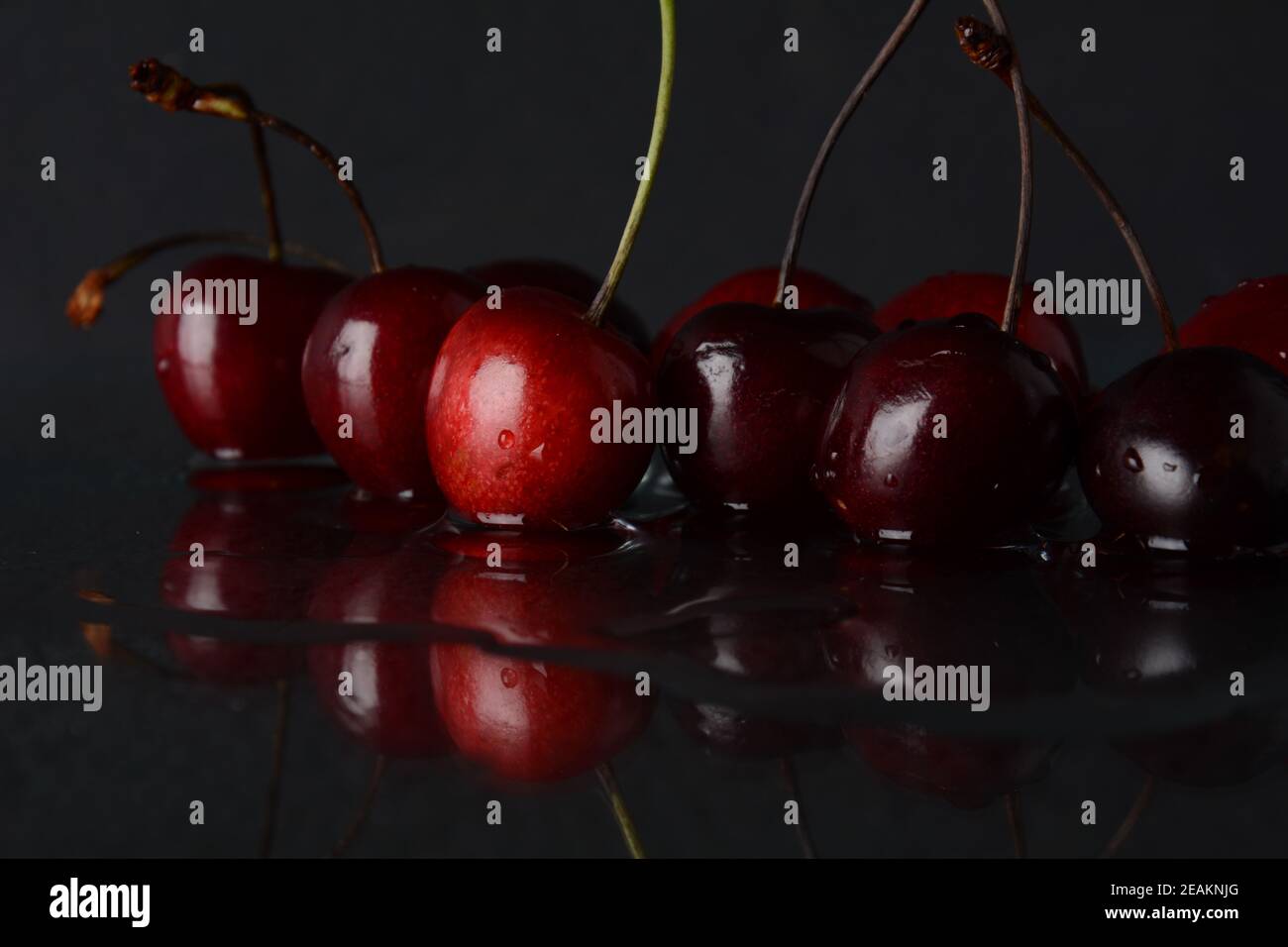 Kirschen, mit Wassertropfen auf schwarzem Hintergrund mit Spiegelung Stockfoto