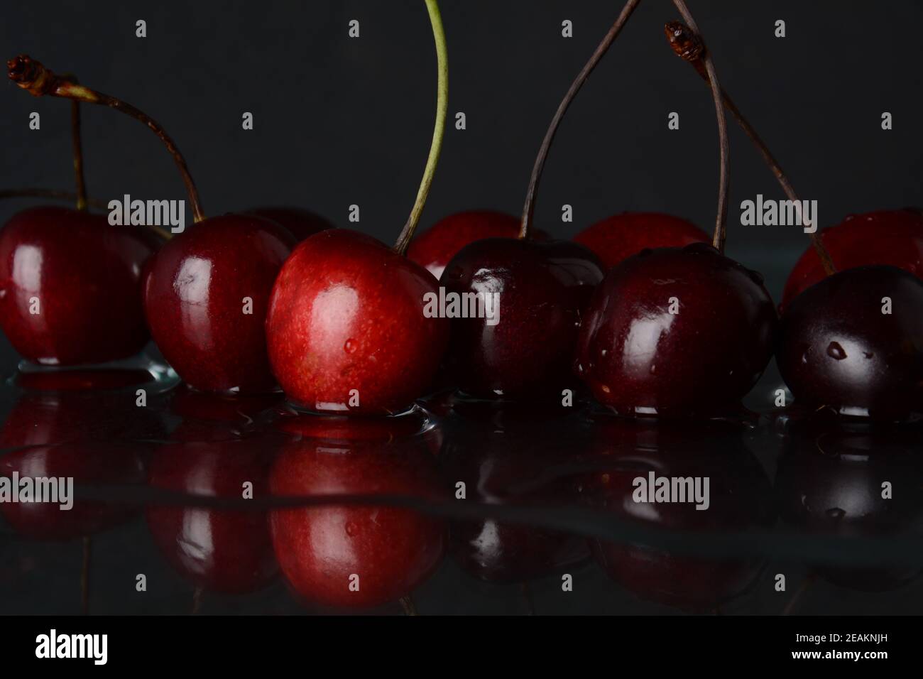 Kirschen, mit Wassertropfen auf schwarzem Hintergrund mit Spiegelung Stockfoto