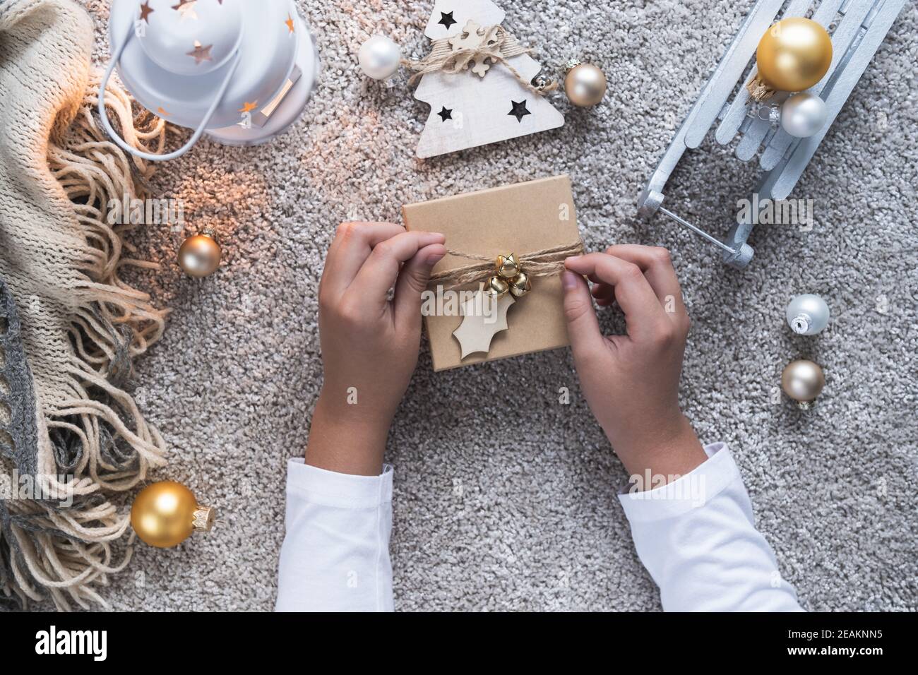 Weihnachtshintergrund mit gemütlicher Winteratmosphäre. Kinderhände öffnen ein Geschenk für das neue Jahr. Stockfoto