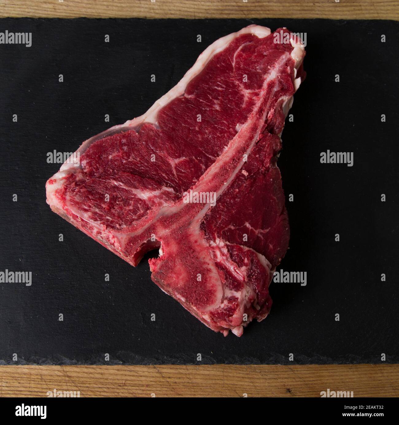 Rohes Fleisch fotografiert auf einem hölzernen Schneidebrett mit einem Schwarzer Hintergrund Stockfoto