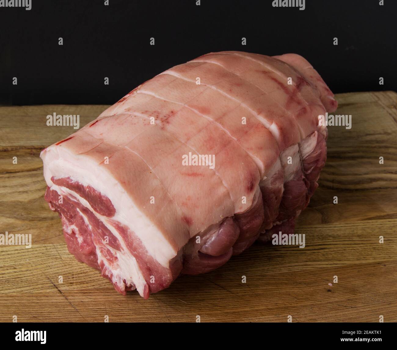 Rohes Schweinefleisch Joint fotografiert auf einem hölzernen Schneidebrett mit Schwarzer Hintergrund Stockfoto