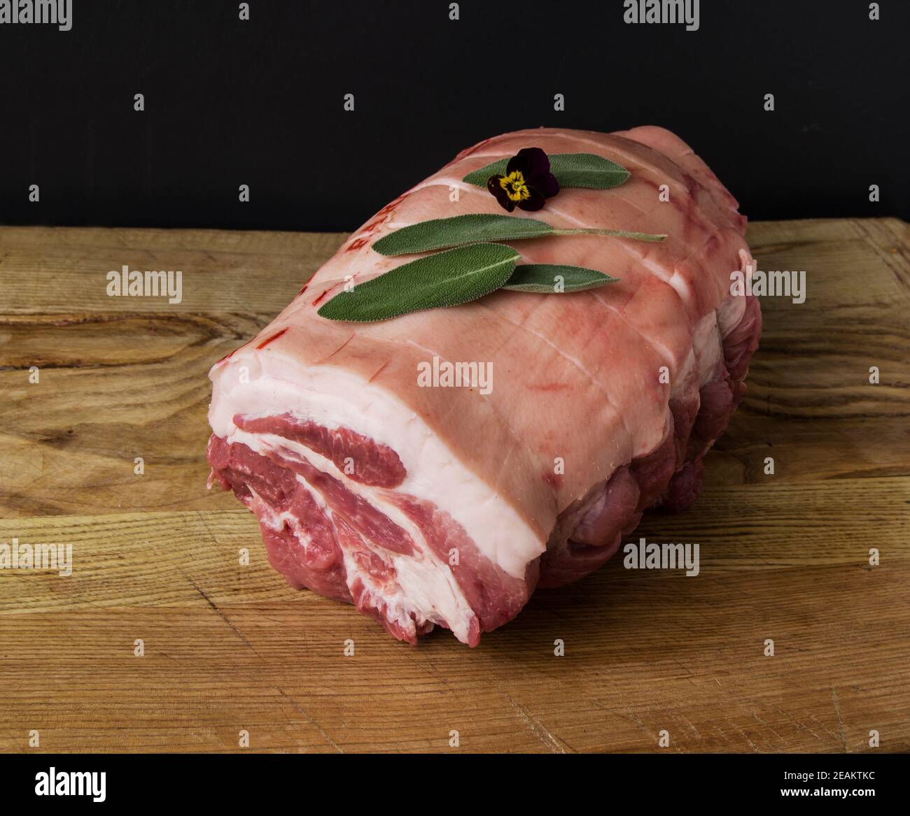 Rohes Schweinefleisch Joint fotografiert auf einem hölzernen Schneidebrett mit Schwarzer Hintergrund Stockfoto