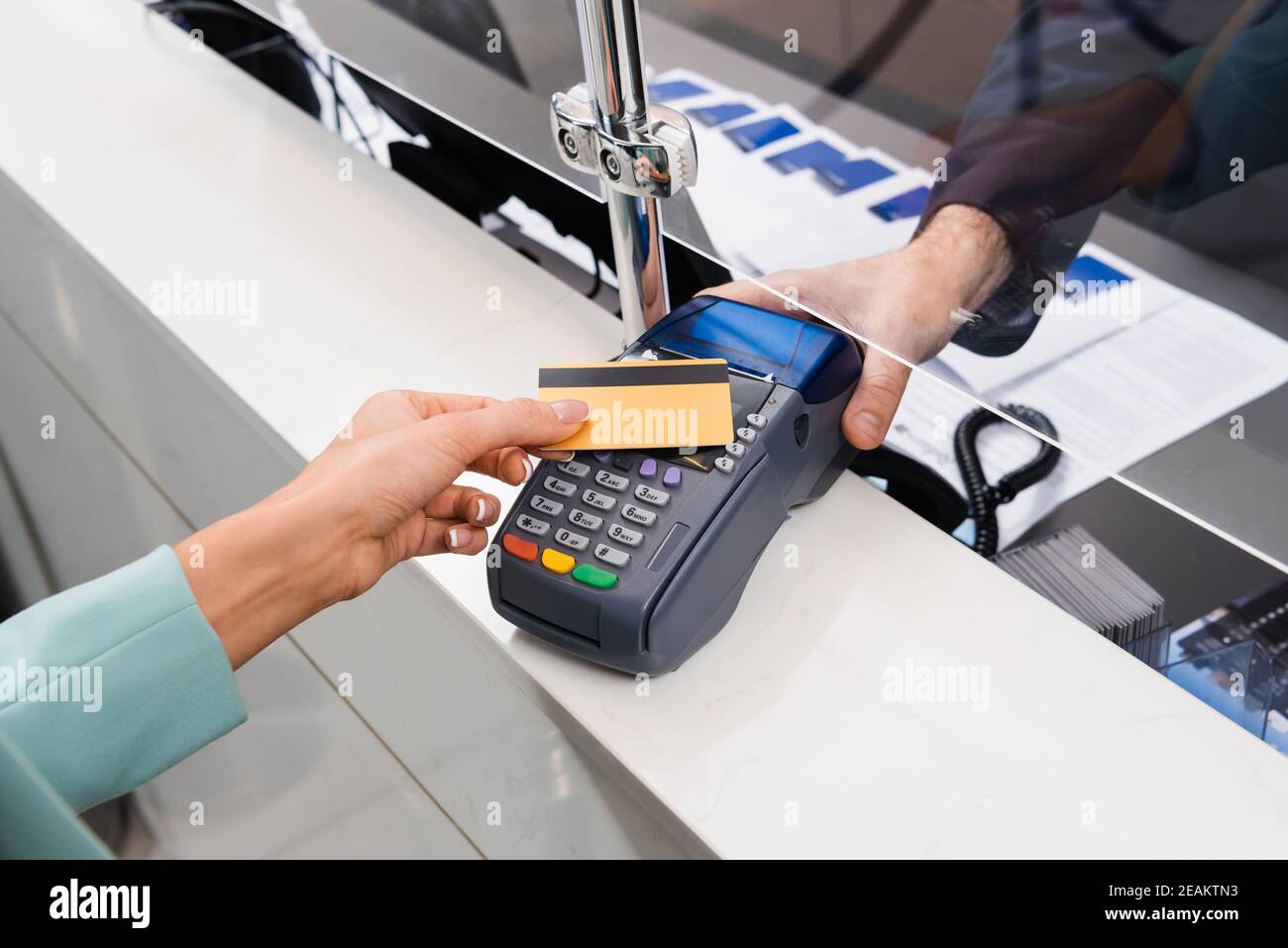 Beschnittene Ansicht der Empfangsdame mit Zahlungsterminal in der Nähe von Frau mit Kreditkarte im Hotel Stockfoto