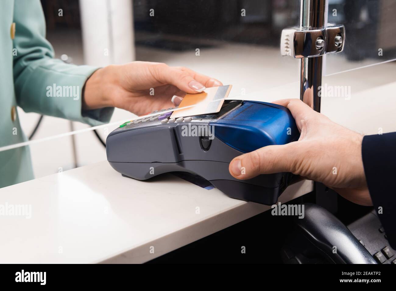 Kurzer Blick auf den Rezeptionisten mit Zahlungsterminal und Frau Mit Kreditkarte in der Hotellobby Stockfoto