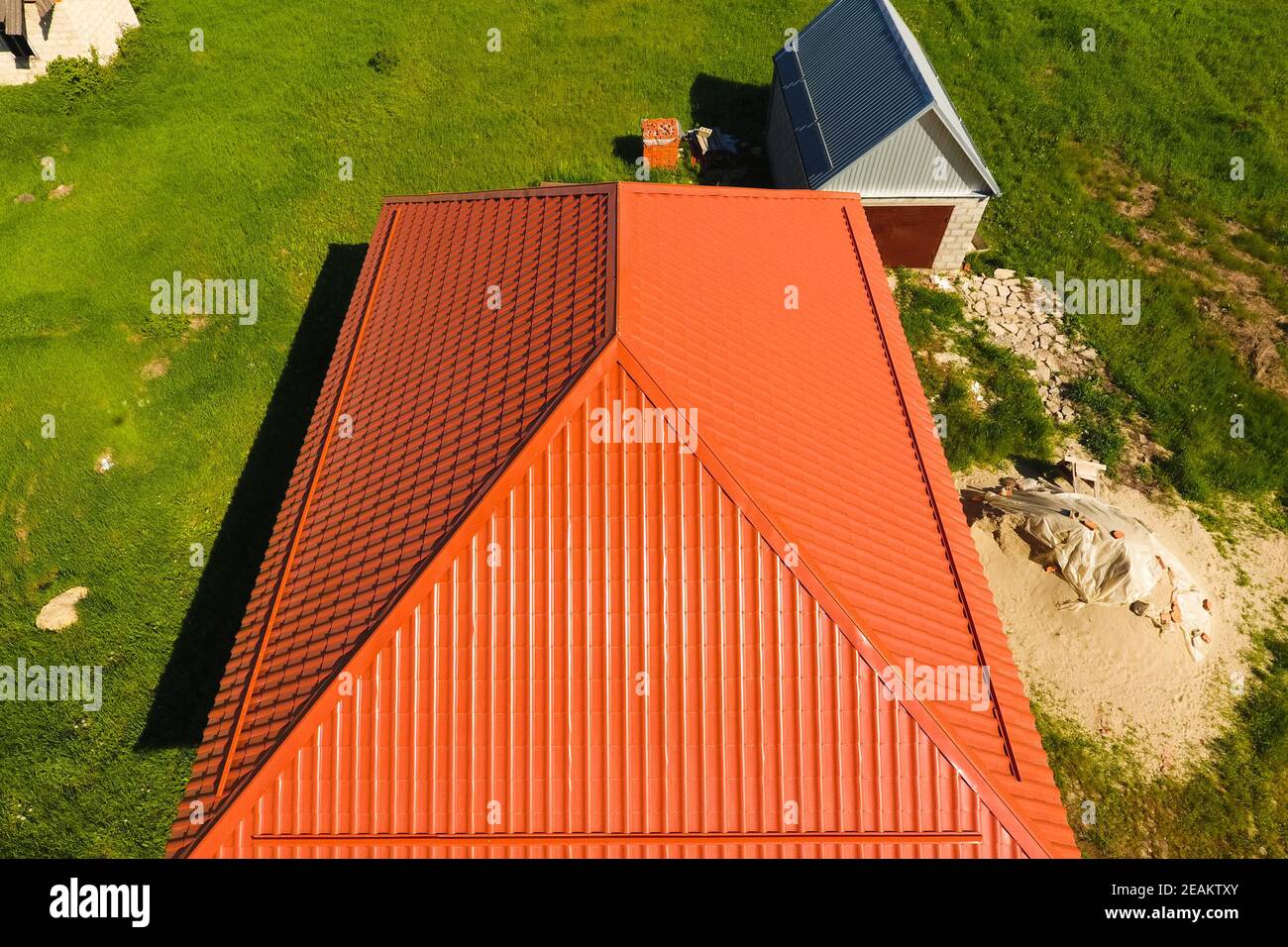 Haus mit einem orangefarbenen Dach aus Metall, Ansicht von oben. Metallische Profil gestrichen Wellpappe auf dem Dach. Stockfoto