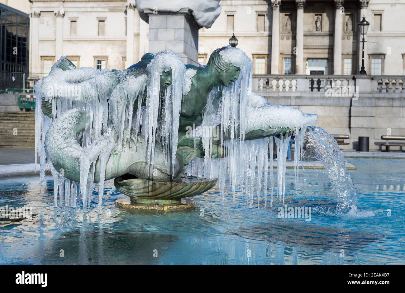 Gefrorene Brunnen Statuen von Trafalgar Square in London. Eiszapfen, die mystisch an einem bronzenen Brunnen hängen Stockfoto