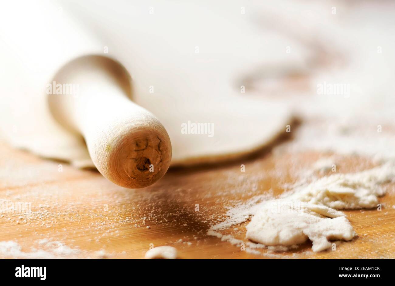 Hölzerne Nudelholz auf einer hölzernen Oberfläche mit etwas Mehl und einem Teig. Stockfoto