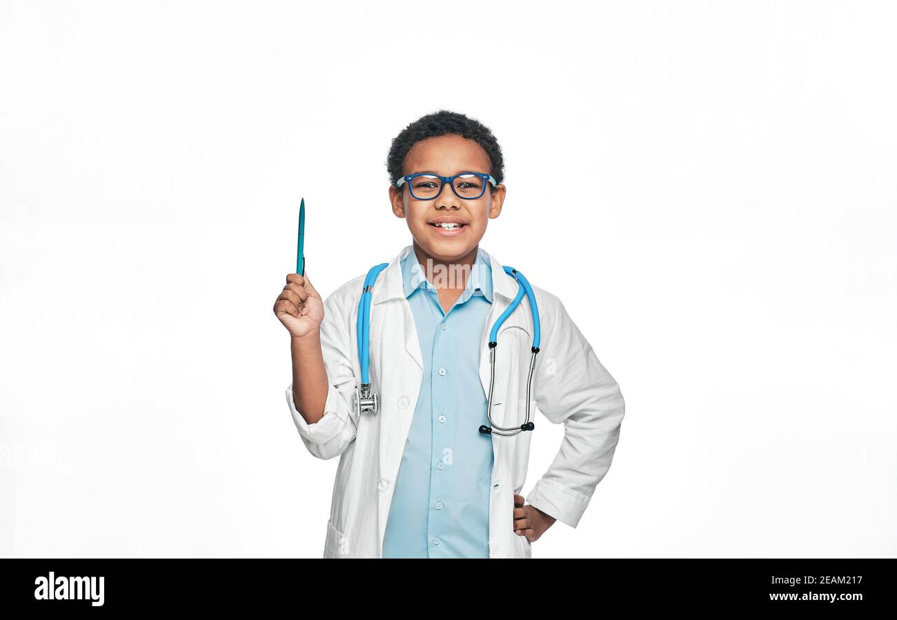 Afroamerikanische männliche Kind trägt einen Arzt Mantel zeigen Stift bis zu leeren Raum, auf weißem Hintergrund Stockfoto