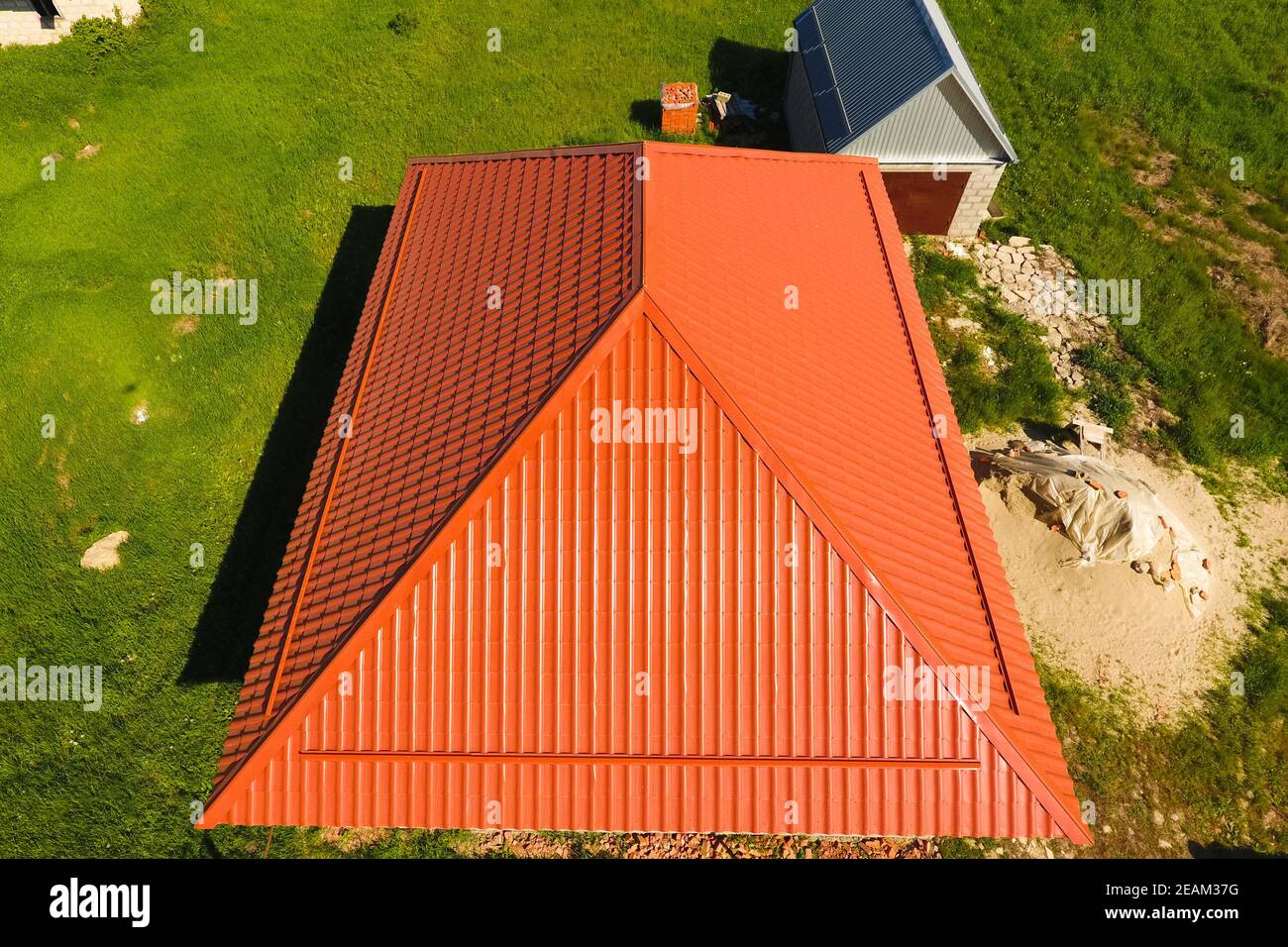 Haus mit einem orangefarbenen Dach aus Metall, Ansicht von oben. Metallische Profil gestrichen Wellpappe auf dem Dach. Stockfoto