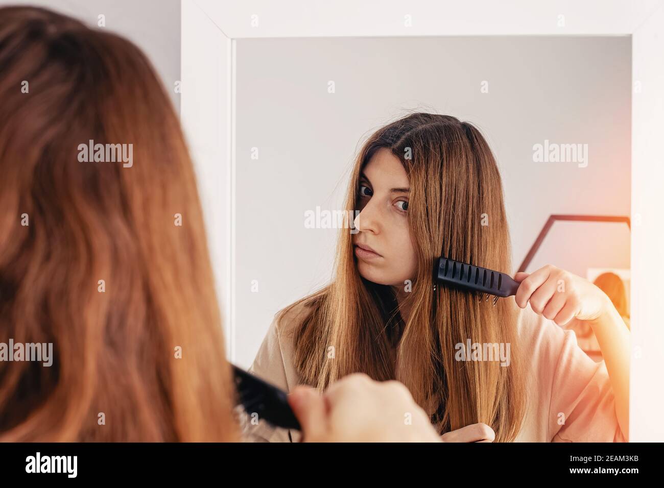 Junge Frau putzt ihr glänzendes langes braunes Haar Stockfoto