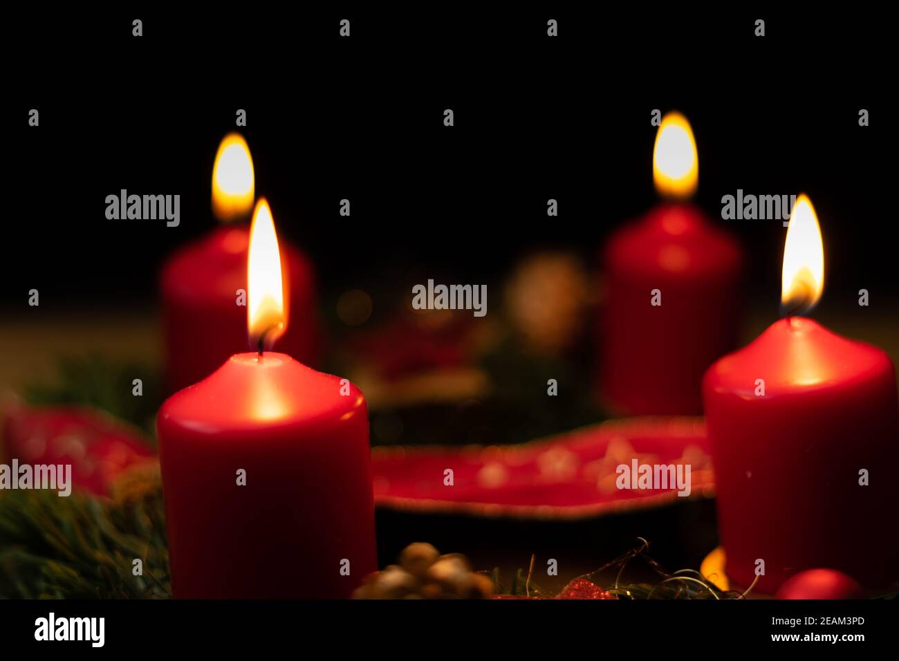 Rote Adventskerze brennt auf weihnachtskranz Stockfoto