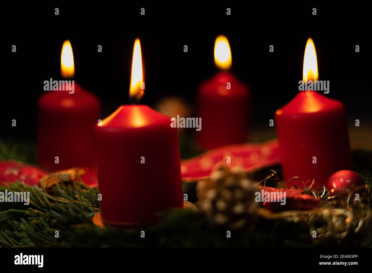 Rote Adventskerze brennt auf weihnachtskranz Stockfoto
